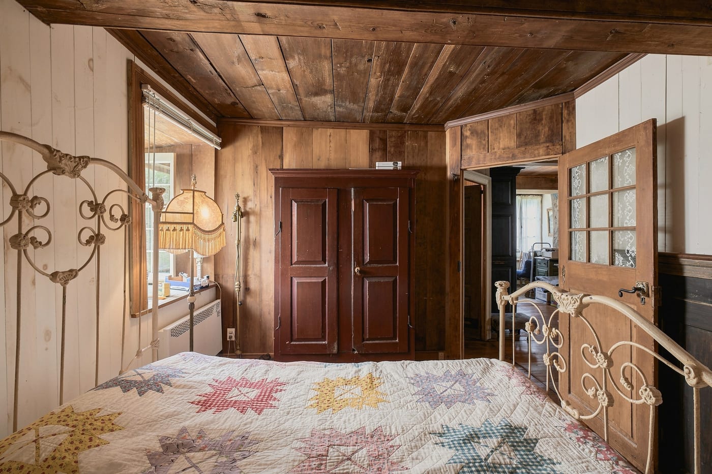 Chambre d'une maison historique à Cap-Santé, lit en fer et courtepointe